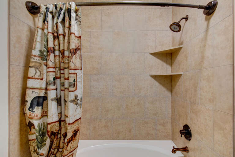 Refresh in your private tub-shower combo with rustic mountain charm, cozy wildlife-themed curtains, and convenient built-in corner shelves for your toiletries.