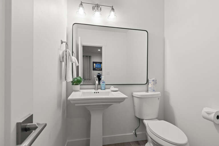 Freshen up in this crisp, modern bathroom with a stylish pedestal sink, sleek mirror, and soft lighting that makes every morning feel bright and inviting.
