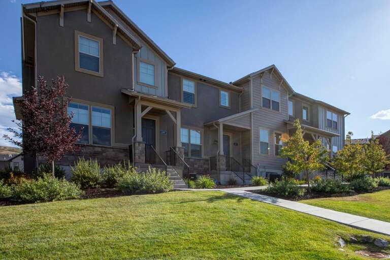 Modern two-story townhomes with stone accents, well-maintained landscaping, and private entrances in a quiet residential neighborhood perfect for a peaceful getaway.