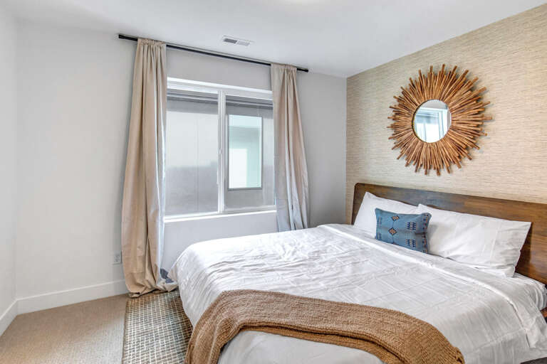 Unwind in this serene bedroom where soft linens, natural textures, and warm tones create your perfect retreat. The sunburst mirror adds charm, while the cozy bed invites restful nights.