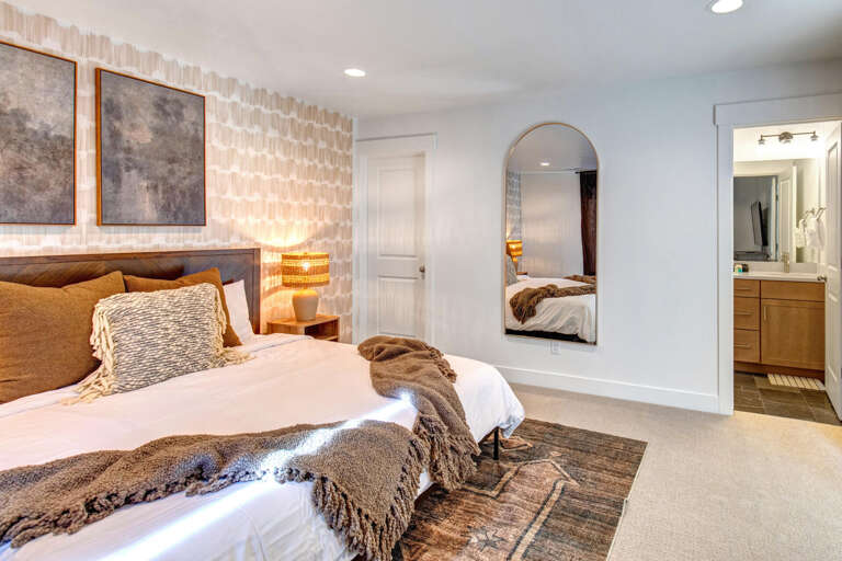 Sink into crisp white linens and cozy textured throws in your serene bedroom retreat, complete with modern furnishings, warm lighting, and a private ensuite bathroom for ultimate comfort.