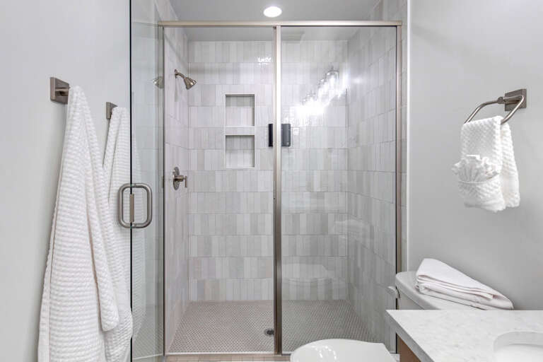 Crisp white tile and modern fixtures create a spa-like oasis for your daily refresh. Fluffy towels and a rainfall shower invite relaxation.
