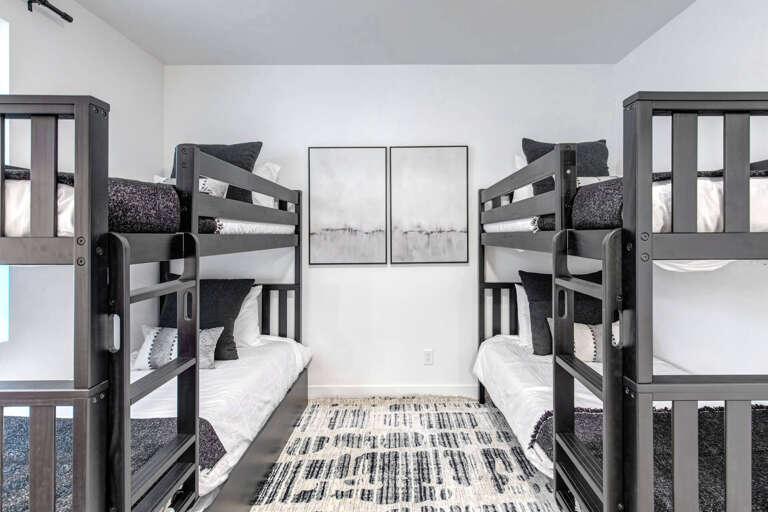 Two sturdy bunk beds frame a cozy room where your group can unwind after adventure-filled days. Crisp linens and charcoal accents bring modern comfort to your restful retreat.