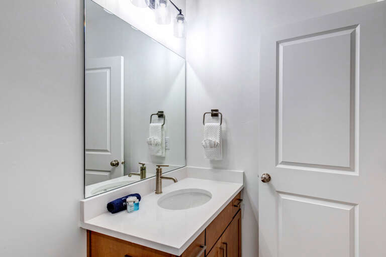 A crisp, modern bathroom awaits you with bright lighting, fresh towels, and a clean vanity—your private retreat after a day of adventure.