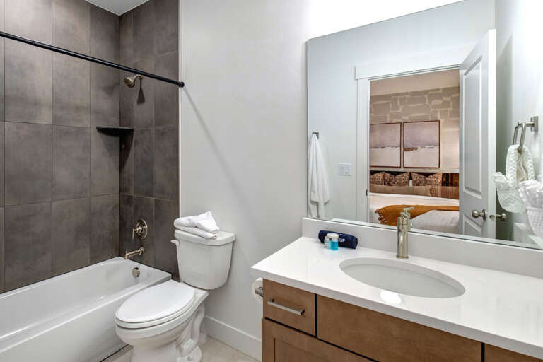 Your private bathroom features sleek gray tile, a spacious vanity, and a soothing tub-shower combo—perfect for unwinding after exploring the area.