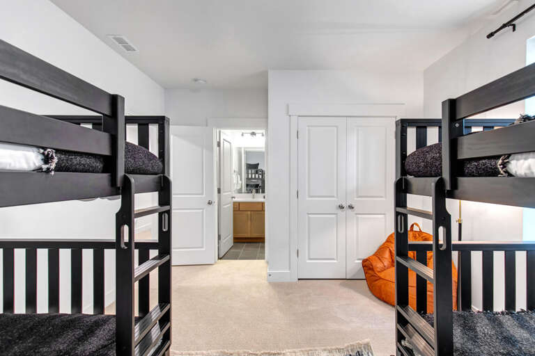 Stretch out in your spacious bunk room with sleek black twin beds, soft carpeting, and an orange bean bag for lounging. Cozy bedding and an ensuite bathroom await you.