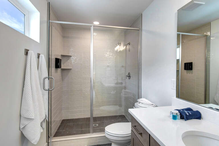 Step into a bright, modern bathroom with sleek tile work, a spacious walk-in shower, and fresh towels waiting for your arrival.