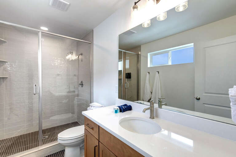 Step into your modern, sunlit bathroom with a spacious walk-in shower, sleek vanity, and fresh towels waiting to wrap you in comfort after a relaxing day.