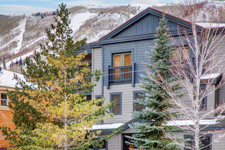 This property sits at the base of ski slopes, framed by evergreens and aspens. It offers convenient access to winter mountain recreation.