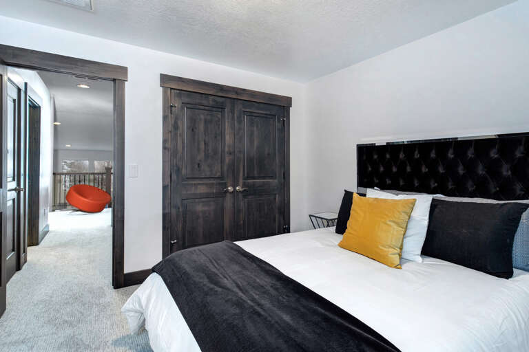 Relax in your peaceful bedroom with its plush tufted headboard, bold accent pillows, and elegant dark wood details. Step through to your private balcony with a cozy seating nook for quiet moments.