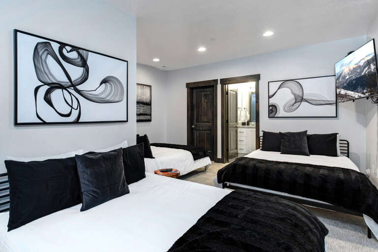 Rest peacefully in your stylish bedroom with two plush beds, modern artwork, and soft lighting. Your private ensuite awaits through the doorway, offering convenience and comfort.