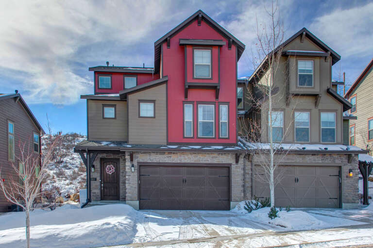 Modern mountain townhomes nestled in a scenic hillside neighborhood, featuring stone accents and private garages, with easy access to surrounding amenities.