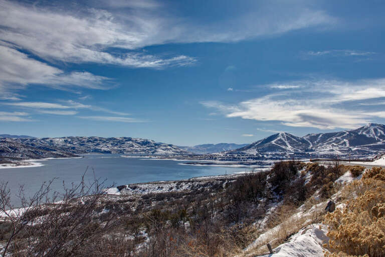A stunning winter landscape frames the property's location, with snow-dusted mountains and a serene lake defining the scenic surroundings.
