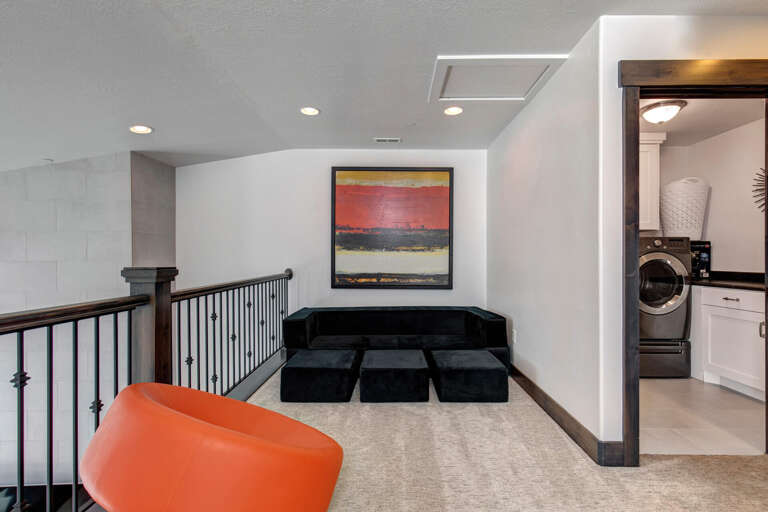 Modern upstairs loft with cozy seating and convenient laundry access—your perfect spot to unwind or catch up on chores in style and comfort.
