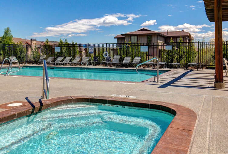 Sparkling turquoise waters invite you to refresh in the pool or soak in the bubbling hot tub under clear blue skies. Lounge chairs and mountain views complete your perfect outdoor escape.