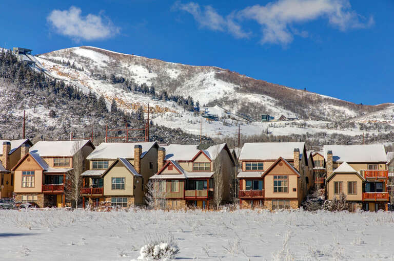 A row of townhomes nestled at the base of a snow-covered ski mountain, offering convenient access to winter slopes and stunning alpine views.