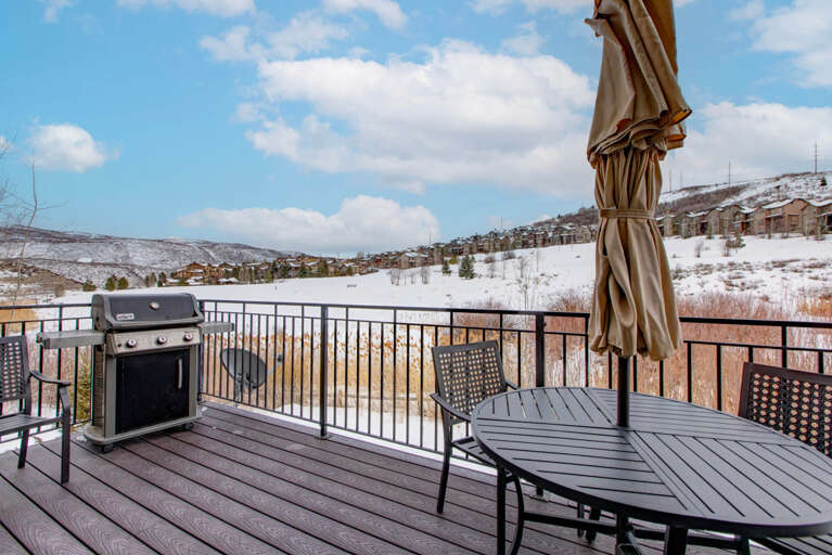 Sweeping winter landscape frames this private deck, complete with a BBQ grill and outdoor seating—perfect for mountain air and relaxation after a day on the slopes.