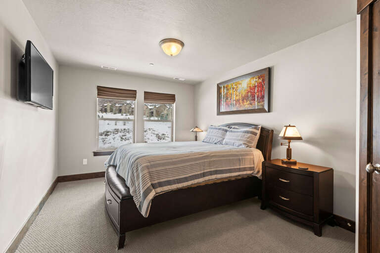 Settle into your cozy bedroom retreat with plush bedding, warm lighting, and peaceful winter views through your windows, perfect for mountain relaxation.