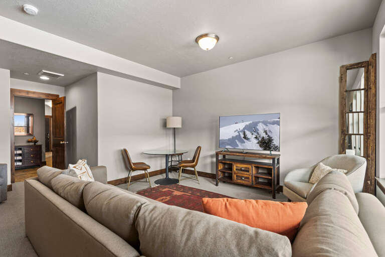 Your spacious living room invites you to unwind on plush sofas with mountain views on the big screen, warm lighting, and a cozy dining nook for morning coffee.