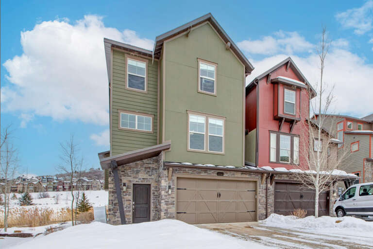 Modern townhome exterior nestled in a peaceful mountain neighborhood, offering convenient parking and easy access to winter activities and scenic surroundings.