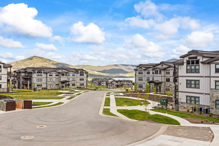 Modern mountain community with multi-story residential buildings set against rolling hills and expansive blue skies, offering a scenic and peaceful setting.