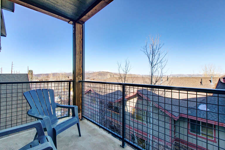 Step onto your private covered balcony with an Adirondack chair perfectly placed for soaking in sweeping mountain and neighborhood views under clear blue skies.