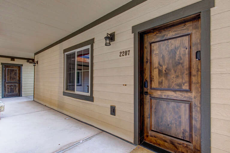 Your private entrance at unit 2207 welcomes you with rustic wood doors, modern farmhouse charm, and a quiet covered porch perfect for morning coffee or evening relaxation.