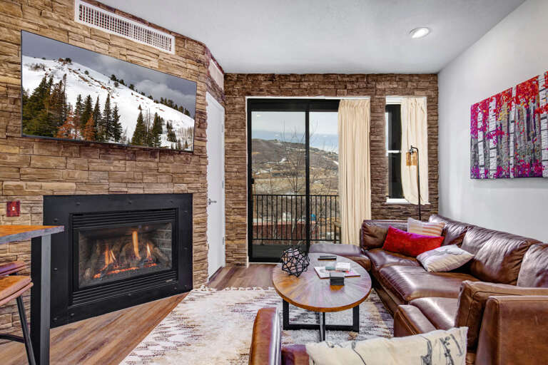 Cozy up by your flickering fireplace in this stylish living room with leather seating and mountain views from your private balcony.