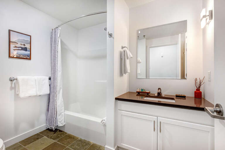 Your private bathroom features a bright, modern design with a relaxing tub-shower combo, sleek vanity with warm lighting, and thoughtful touches throughout.