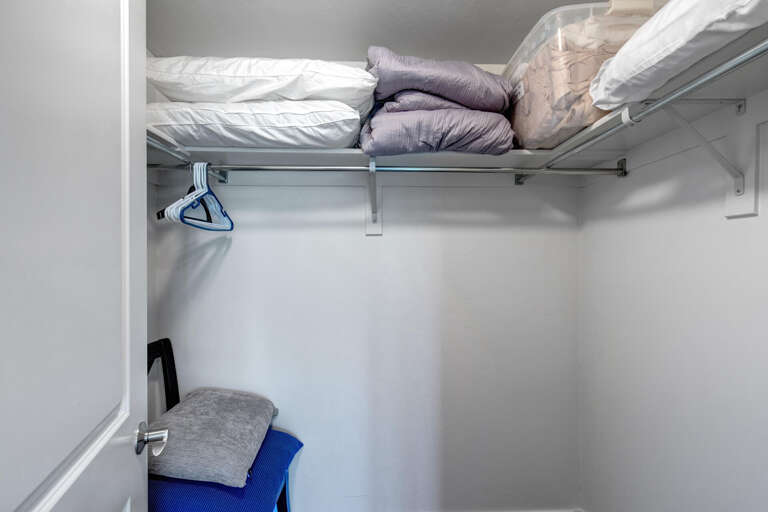 Your closet offers convenient storage with hanging space and upper shelves stocked with fresh linens, keeping everything organized and within easy reach throughout your stay.