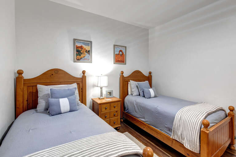 Unwind in your peaceful bedroom where twin beds dressed in soft blue linens welcome you after a day of adventure. National Park posters add a touch of mountain charm.
