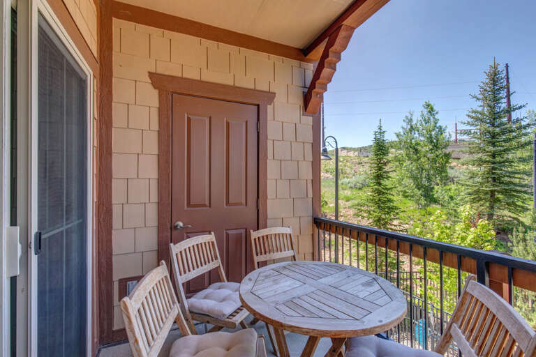 Private balcony overlooking evergreen-studded hills offers your peaceful mountain retreat with cozy outdoor dining beneath covered shelter.