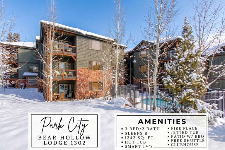 A winter view of Bear Hollow Lodge 1302 in Park City, with snow-dusted trees framing the multi-story building and heated pool area.