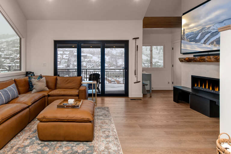 Cozy up in this stylish living room with leather seating, fireplace warmth, and stunning mountain views from your private balcony.