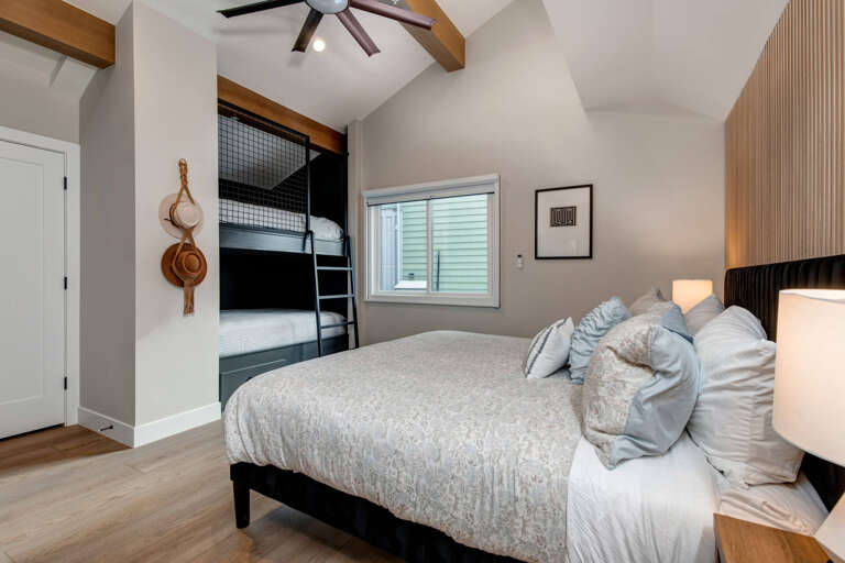 Rest in your stylish bedroom featuring exposed beams, built-in bunks, and modern comfort for the perfect family retreat.