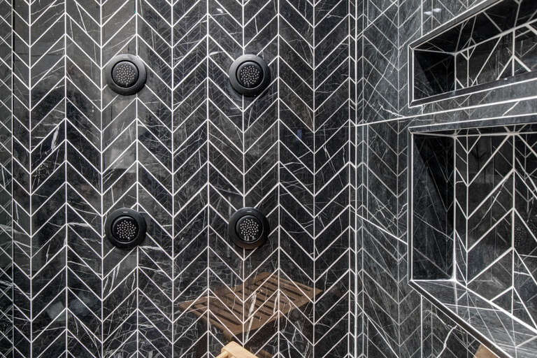 Upper Main 301: Your private spa awaits with stunning geometric marble walls and dual rainfall showerheads for a luxurious cleansing experience.