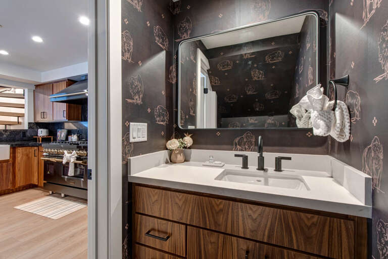Upper Main 301: Freshen up in this stylish half bathroom located adjacent to the kitchen, featuring bold botanical wallpaper and sleek modern fixtures. Perfect for a quick touch-up.