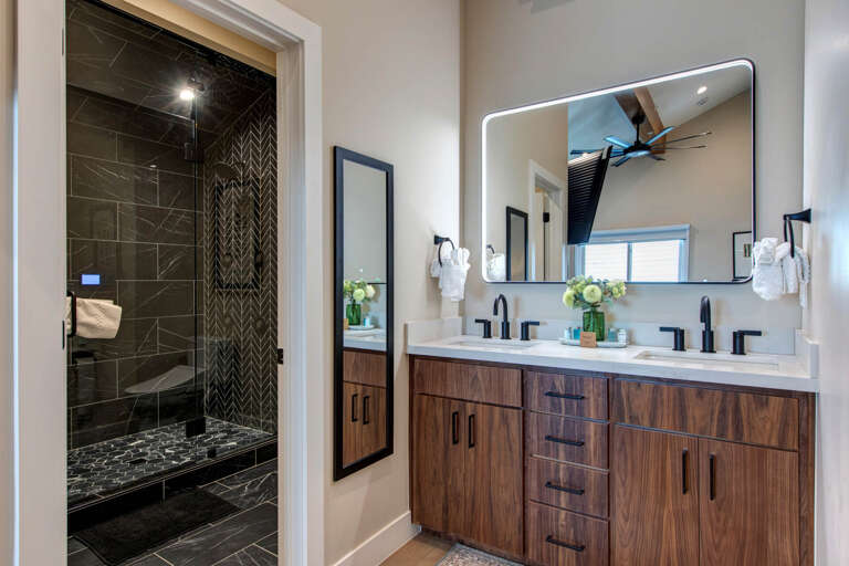Step into your spa-like ensuite with dual vanity, backlit mirror, and luxurious marble shower featuring stunning geometric tilework.
