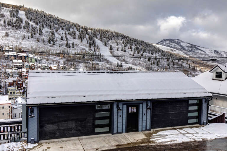 Modern mountain retreat nestled in a snowy alpine valley with ski slopes and scenic mountain peaks surrounding the property.