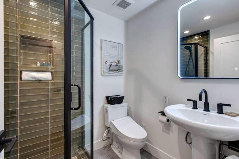 Step into your sleek, modern bathroom featuring a walk-in shower with elegant tiled walls, crisp white fixtures, and a stylish backlit mirror—your private sanctuary for relaxation.