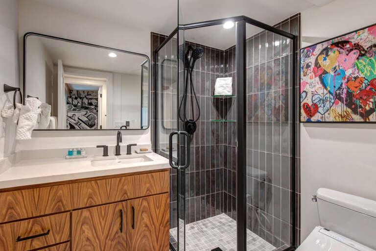 Step into your stylish private bathroom featuring a sleek glass-enclosed shower, modern vanity, and tasteful artwork that adds personality to your space.