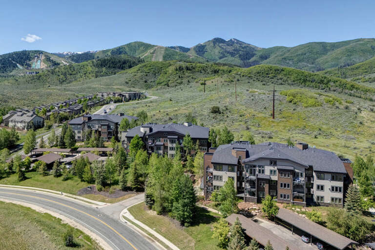 This mountain property sits nestled at the base of scenic alpine terrain, surrounded by forested peaks and lush green hillsides. The property offers convenient access to ski slopes and natural beauty year-round.