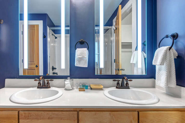 Refresh in your spacious dual-sink bathroom, styled in calming blue tones with bright LED mirrors and fresh towels ready for your stay.