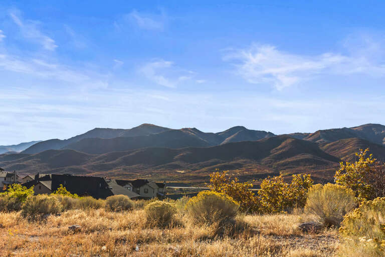 A vacation rental property nestled in an autumn desert landscape, with golden-hued vegetation and dramatic mountain vistas framing the neighborhood.