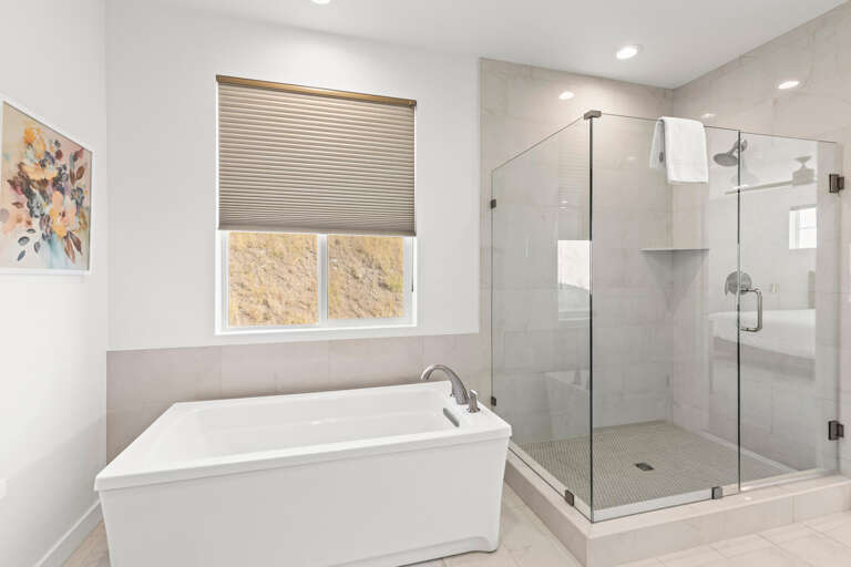 Your private retreat features a luxurious soaking tub and spacious glass-enclosed shower with elegant tile work, perfect for unwinding after a day of adventure.