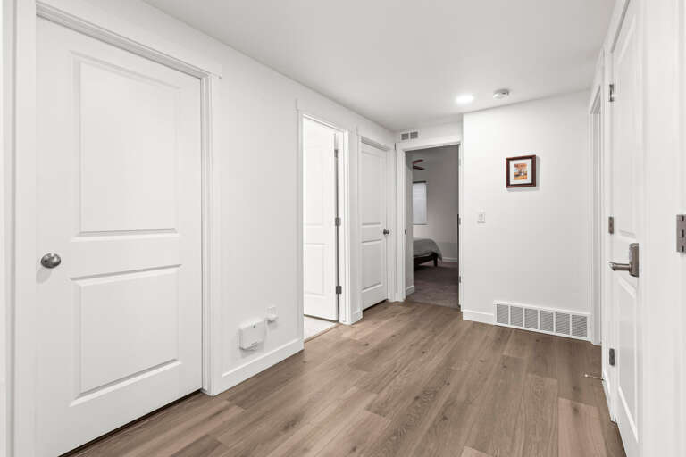 Your hallway connects comfortable living spaces with warm wood-look flooring and thoughtful details like the framed art guiding you to your private bedroom retreat.