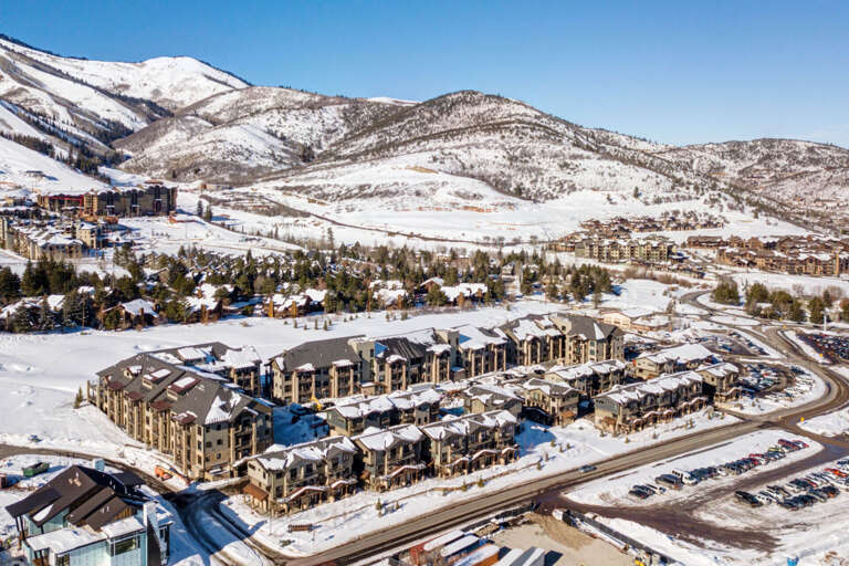 Aerial view of a mountain resort community nestled in snow-covered peaks, showcasing the property's location within a scenic winter landscape and ski area.