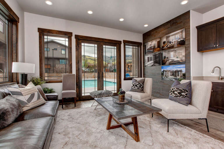 Picture yourself unwinding in this stylish living room, where natural light pours through expansive windows framing serene pool views. Sink into plush seating and let the modern mountain elegance surround you.