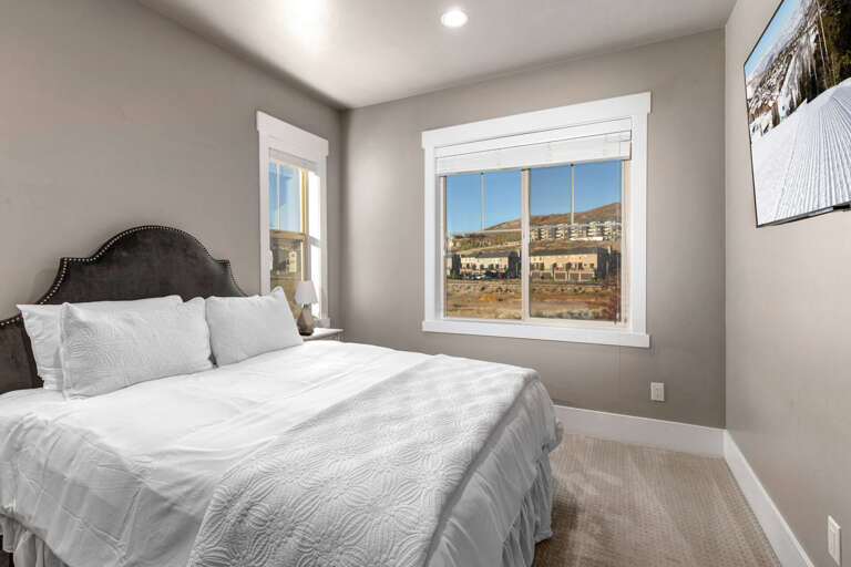 Sink into crisp white linens and wake to sunlit mountain views—your peaceful retreat awaits in this cozy bedroom designed for restful nights.