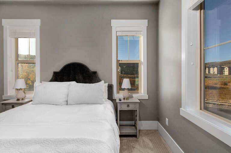 Wake up to natural light streaming through large windows framing serene views. Crisp white linens and elegant furnishings create your peaceful retreat.